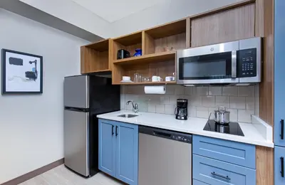 a kitchen with blue cabinets and a stainless steel refrigerator at Candlewood Suites Erlanger - South Cincinnati by IHG in Erlanger