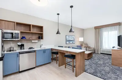 an open kitchen with blue cabinets and a living room at Candlewood Suites Erlanger - South Cincinnati by IHG in Erlanger