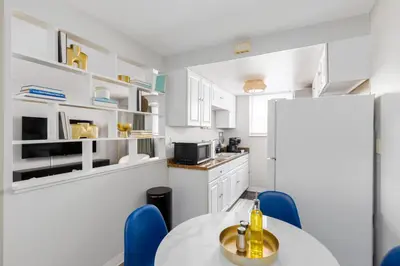 a white kitchen with a table and blue chairs at Maple Heights Gem Libby Unit 1 in Maple Heights