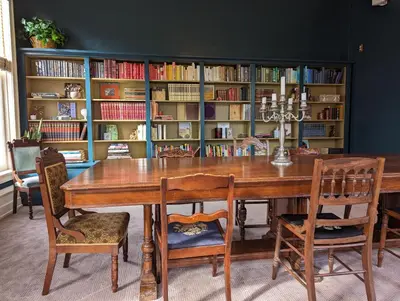 a dining room table with chairs and a book shelf with books at The Vistula Rose B & B in Toledo