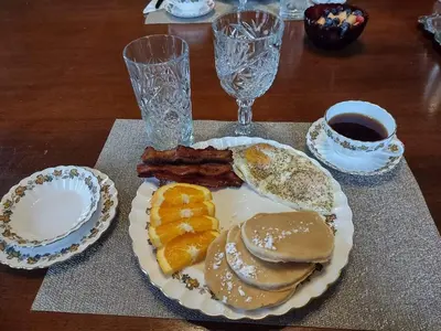 a plate of food with pancakes and bacon on a table at The Vistula Rose B & B in Toledo