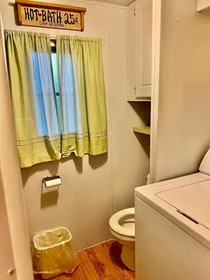 a bathroom with a toilet and a yellow curtain at White Caps Motel and RV Park in Port Clinton