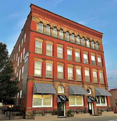a large red brick building on a city street at The Voegele Historic Lofts in Mansfield