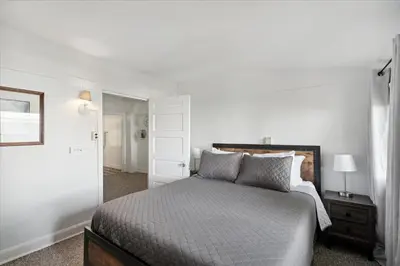 a white bedroom with a bed and a mirror at Lakefront Family Home/Golf Cart/Beach in Luna Pier