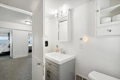 a white bathroom with a sink and a mirror at Lakefront Family Home/Golf Cart/Beach in Luna Pier