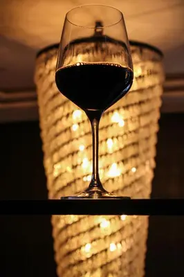 a glass of wine in front of a chandelier at Metropolitan at The 9, Autograph Collection in Cleveland
