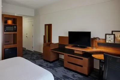 a hotel room with a bed and a desk with a television at Fairfield Inn & Suites by Marriott Columbus Airport in Columbus