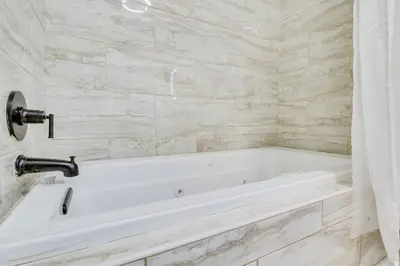 a white bath tub in a bathroom with marble walls at Jetted Tub Dayton Condo, 2 Mi to Oregon District in Dayton