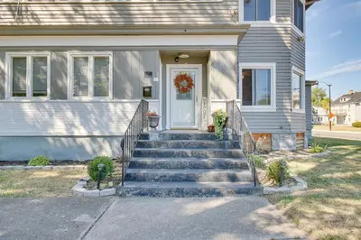a white house with stairs leading to a door at Jetted Tub Dayton Condo, 2 Mi to Oregon District in Dayton
