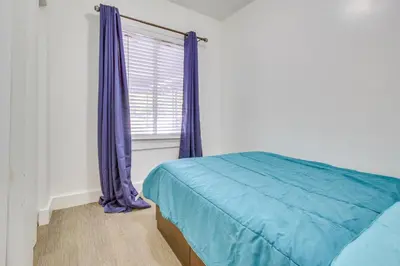 a bedroom with a bed and a window with purple curtains at Convenient Dayton Vacation Rental Near Downtown! in Dayton