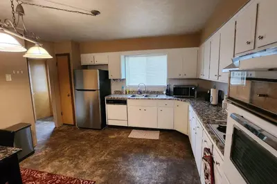 a kitchen with white cabinets and a stainless steel refrigerator at Tastefully Furnished 3bd @Euclid in Euclid