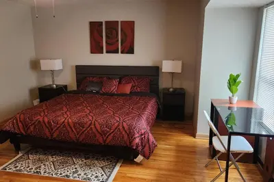 a bedroom with a bed with a red comforter and a desk at Tastefully Furnished 3bd @Euclid in Euclid