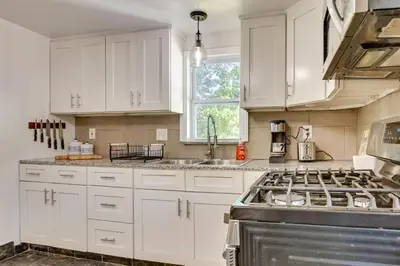 a kitchen with white cabinets and a stove top oven at Modern Northfield Cottage with Yard! in Northfield