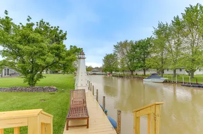 a dock with a bench and a lighthouse on a river at Hot Tub, Lake Access, and Dock Port Clinton Retreat in Port Clinton