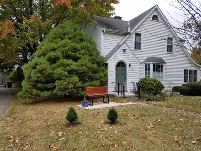 a white house with a bench in the yard at 1936 Art & International Home in Lancaster