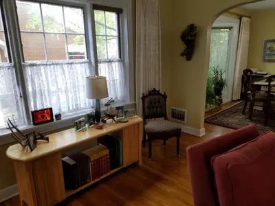 a living room with a desk and a chair and windows at 1936 Art & International Home in Lancaster