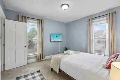 a bedroom with blue walls and a bed and a window at The Indiana Stunner in Columbus