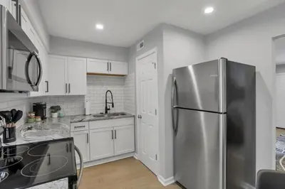 a kitchen with a stainless steel refrigerator and white cabinets at The Schumacher Townhouse - 2 BR in Columbus
