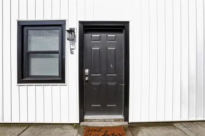 a black door and a window on a white house at The Schumacher Townhouse - 2 BR in Columbus