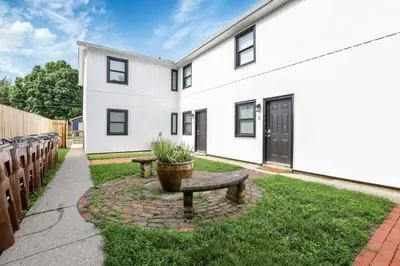 a white house with a bench in the yard at The Schumacher Townhouse - 2 BR in Columbus