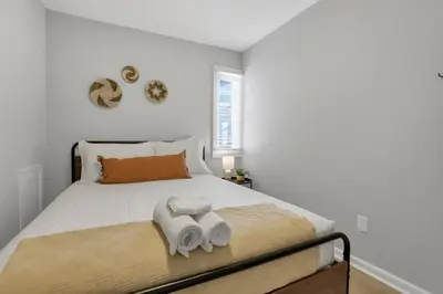 a white bedroom with a bed with towels on it at The Schumacher Place - NEW 2 BR in Columbus