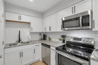 a kitchen with white cabinets and stainless steel appliances at The Schumacher Place - NEW 2 BR in Columbus