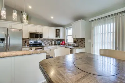 a kitchen with white cabinets and a wooden table at 5 Mi to The USAF Museum Dayton Home, Walk to Park in Dayton