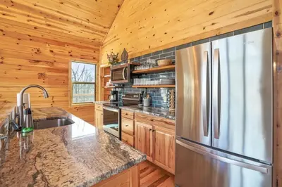 a kitchen with a stainless steel refrigerator and wooden walls at Fern Woods A modern take on Hocking Hills cabins in McArthur