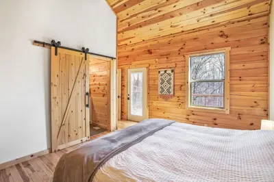 a bedroom with a bed in a wooden room at Fern Woods A modern take on Hocking Hills cabins in McArthur