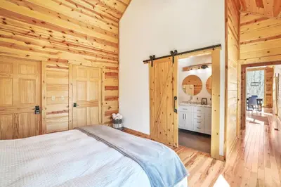 a bedroom with a bed and wooden walls at Fern Woods A modern take on Hocking Hills cabins in McArthur
