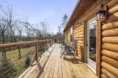 a wooden deck with chairs on the side of a cabin at Fern Woods A modern take on Hocking Hills cabins in McArthur