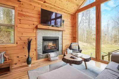 a living room with a fireplace and a tv at Fern Haven A modern take on Hocking Hills cabins in McArthur
