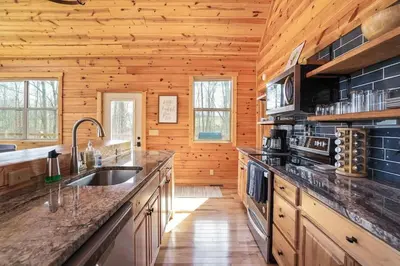 a kitchen with wooden walls and a wooden floor at Fern Haven A modern take on Hocking Hills cabins in McArthur