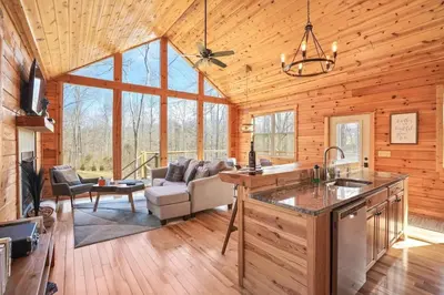 a kitchen and living room of a log cabin at Fern Haven A modern take on Hocking Hills cabins in McArthur