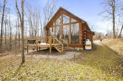 a log cabin in the woods with a large window at Fern Haven A modern take on Hocking Hills cabins in McArthur