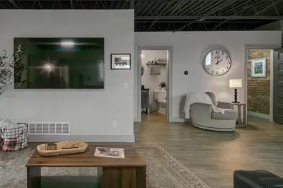 a living room with a table and a clock on the wall at The 418. An 1866 Build with Modern Comforts in Fort Wayne
