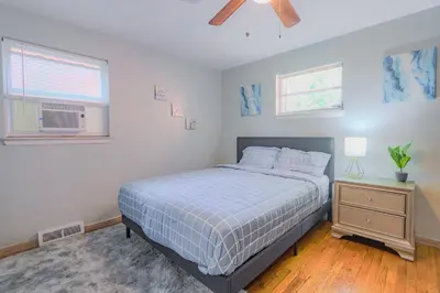 a bedroom with a bed and a nightstand and two windows at Charming 2 Bed Room in Cleveland in Cleveland Heights