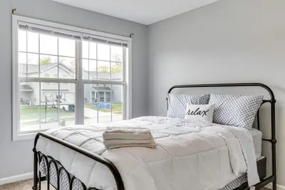 a white bedroom with a bed and a large window at Cozy Ohio Home - Deck, Arcade Games and Near Golfing in Cincinnati
