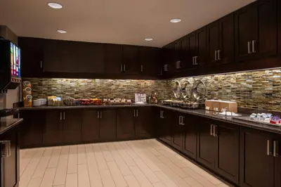 a kitchen with dark wood cabinets and a brick wall at Residence Inn by Marriott Akron Fairlawn in Fairlawn