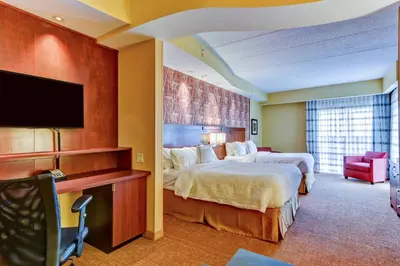 a hotel room with two beds and a flat screen tv at Courtyard by Marriott Bridgeport Clarksburg in Bridgeport