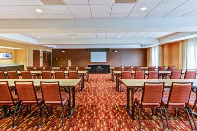a conference room with tables and chairs and a screen at Courtyard by Marriott Bridgeport Clarksburg in Bridgeport