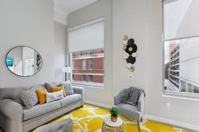 a living room with a couch and a mirror at Downtown Stroll to the Bengals in Cincinnati
