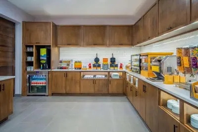 a large kitchen with wooden cabinets and a refrigerator at Home2 Suites By Hilton West Chester Cincinnati in West Chester