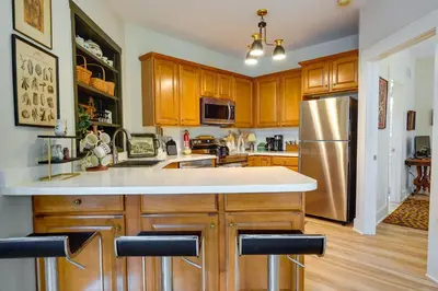 a kitchen with wooden cabinets and a stainless steel refrigerator at Charming Granville Home with Porch - Walk Downtown! in Granville
