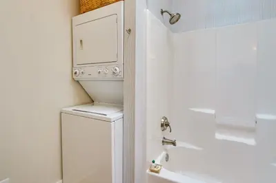 a bathroom with a washer and dryer next to a tub at Charming Granville Home with Porch - Walk Downtown! in Granville