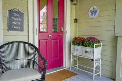 a pink door on a porch with a basket of flowers at Charming Granville Home with Porch - Walk Downtown! in Granville