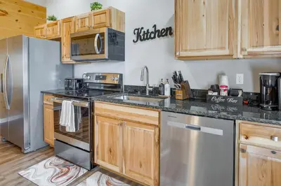 a kitchen with wooden cabinets and stainless steel appliances at Serene Logan Retreat with Hot Tub and Stargazing Dome in Logan
