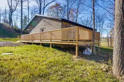 a small cabin with a deck in the woods at Serene Logan Retreat with Hot Tub and Stargazing Dome in Logan
