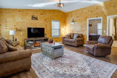 a living room with leather furniture and a flat screen tv at Serene Logan Retreat with Hot Tub and Stargazing Dome in Logan