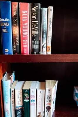 a row of books sitting on a book shelf at Spacious Five-Bedroom Bliss in Fairlawn